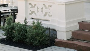 An outdoor seating area with tables and chairs, a white decorative structure, and a building with large windows in the background. - Wilbur Mansion (Bethlehem)