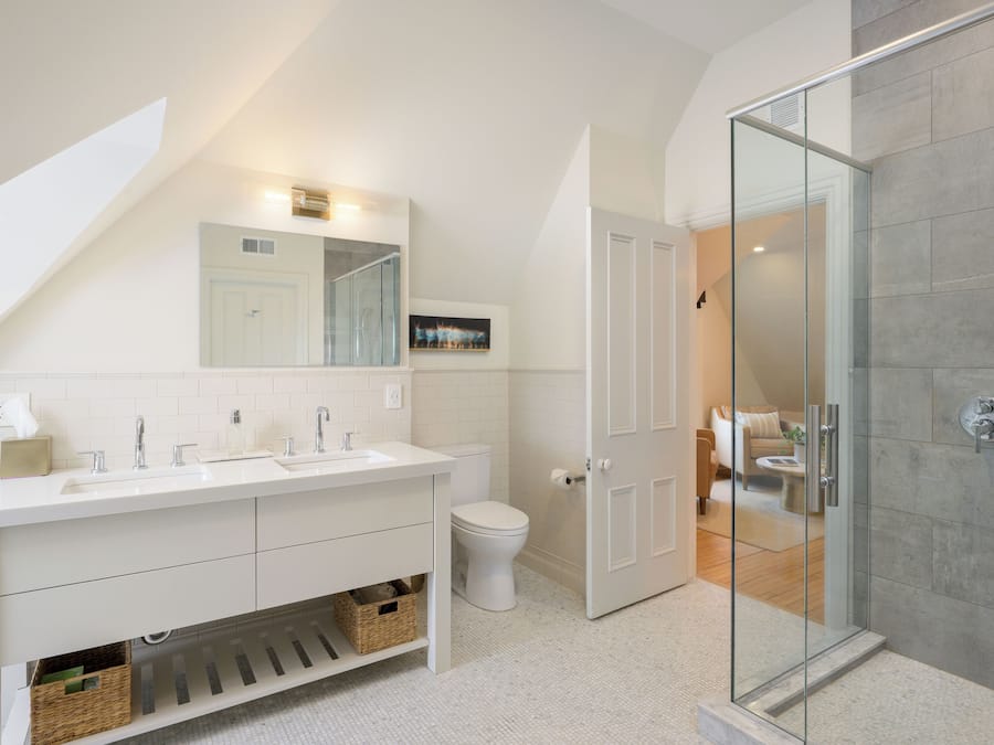 Ein modernes Badezimmer mit einem weißen Waschtisch, einer Duschkabine aus Glas und einer sichtbaren Toilette.