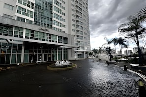 A modern hotel with a large glass facade, a central courtyard with a fountain, and palm trees. - Saint Moritz com vista espetacular de Brasilia (Brasília)