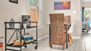 Ein Zimmer mit einem Kaffeewagen, Korbstühlen, einem Esstisch und einem Bett.