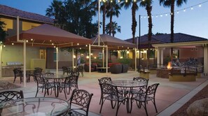 Relax in a serene outdoor space with comfortable seating, umbrellas, and a fire feature.