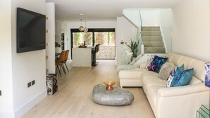 A spacious living area with a sofa, a coffee table, and a TV mounted on the wall. - Sail Loft (Dawlish)