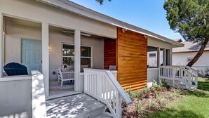 A two-story house with a covered porch, a wooden deck, and a small outdoor seating area.