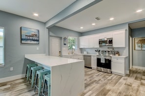 A modern kitchen with white cabinets, a central island, and bar stools.