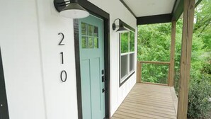 A wooden deck with a teal door and a number '210' on the wall.