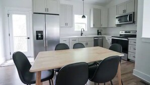 A modern kitchen with white cabinets, a wooden dining table, and black chairs.