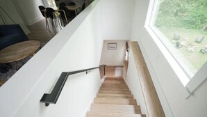 A staircase with wooden steps and a black handrail, leading to a dining area with a table and chairs.
