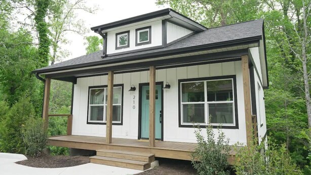 A two-story house with a front porch, a green door, and a number '210' on the wall.