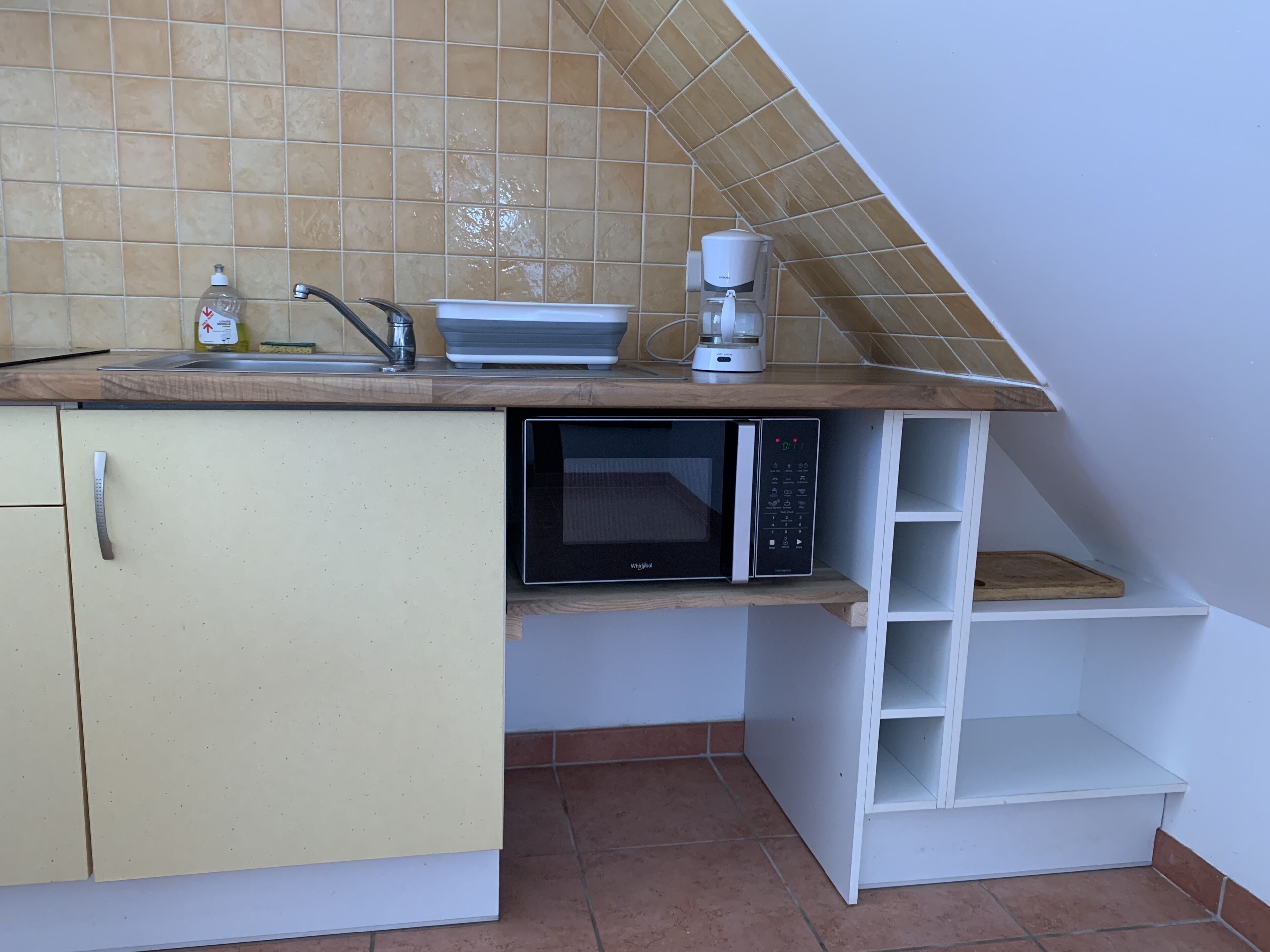 A compact kitchen with a microwave, coffee maker, and a small sink.