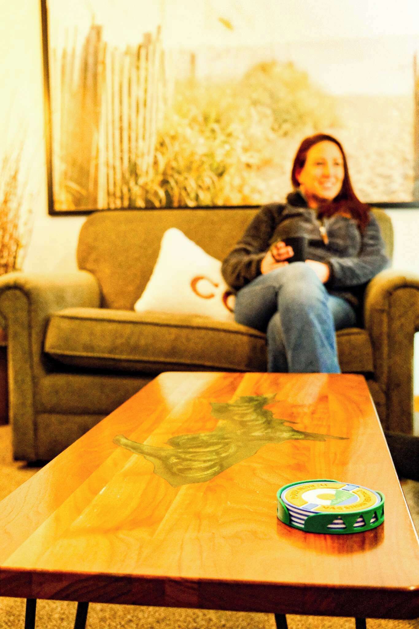 Een persoon zit op een bank met een tafel ervoor.