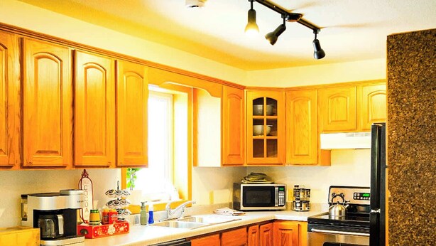 Une cuisine avec des meubles de rangement en bois, un four à micro-ondes, une cuisinière et un réfrigérateur.