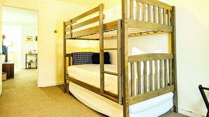 A bunk bed with a wooden frame and white bedding in a room with beige carpet and white walls. - Aurora Loft | 2BR | ORV Trail 2 + Iron Belle (Ironwood)