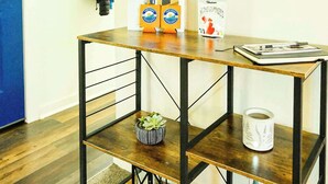 A room with a wooden desk, a blue door, a coat rack with jackets, a framed animal silhouette, a wreath, and a snack box. - Aurora Loft | 2BR | ORV Trail 2 + Iron Belle (Ironwood)