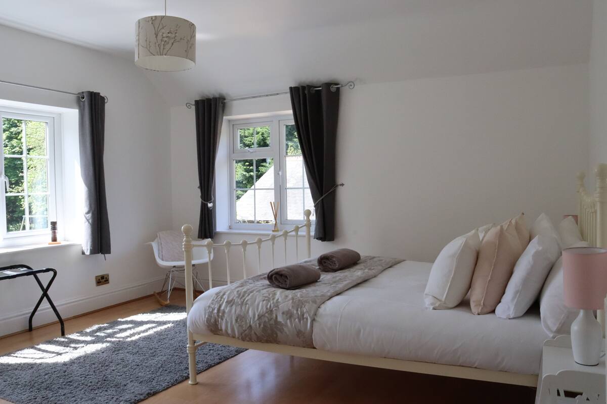 Ein Schlafzimmer mit einem Bett, einem Fenster, einem Sessel und einer Lampe.