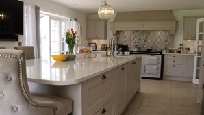 Een moderne keuken met een groot eiland, witte kastjes en een kroonluchter.