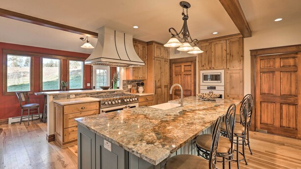 A kitchen with wooden cabinets, a granite island, and a large window.
