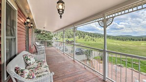 A wooden porch with wicker furniture and a view of a green landscape.