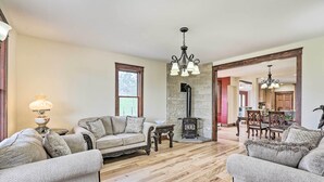 A spacious living room with a fireplace, a dining area, and a kitchen in the background.
