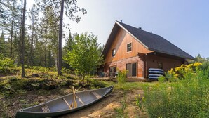 A cabin with a large deck, surrounded by forest. - L'Anse 750 sur la rivière Sacacomie (Saint-Alexis-des-Monts)