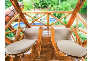 Une terrasse en bois avec deux chaises rembourrées et une rambarde en bois.