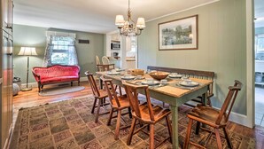A dining area with a wooden table, chairs, a chandelier, and a red sofa. - Londonderry Retreat ~ 3 Mi to Lowell Lake! (Londonderry)