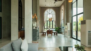 Een ruime woonkamer met een bank, een glazen salontafel en een eethoek met een tafel en stoelen.