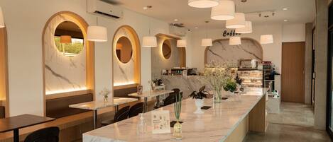 A modern cafe interior with marble countertops, pendant lighting, and a coffee bar.