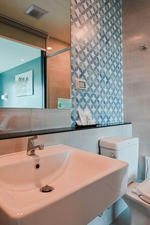 A modern bathroom with a white sink, a toilet, and a patterned wall.