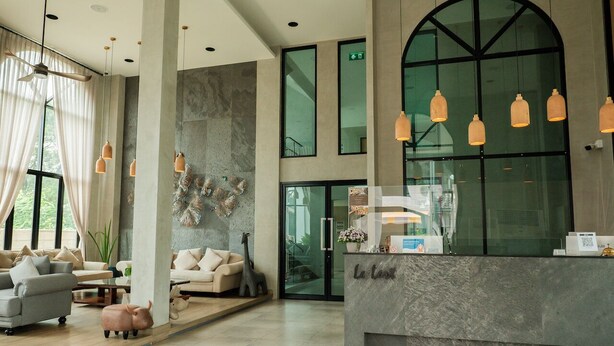 Een moderne lobby met een receptiebalie, een zithoek en grote ramen.
