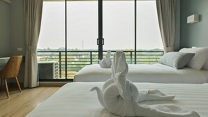 Een hotelkamer met twee bedden, uitzicht op de omgeving en een stoel.