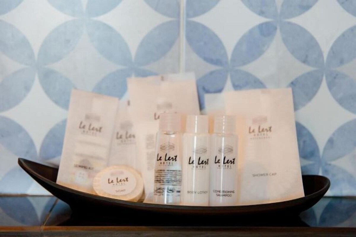 A tray with Le Lest Hotel toiletries including body lotion, conditioner, and shower cap.
