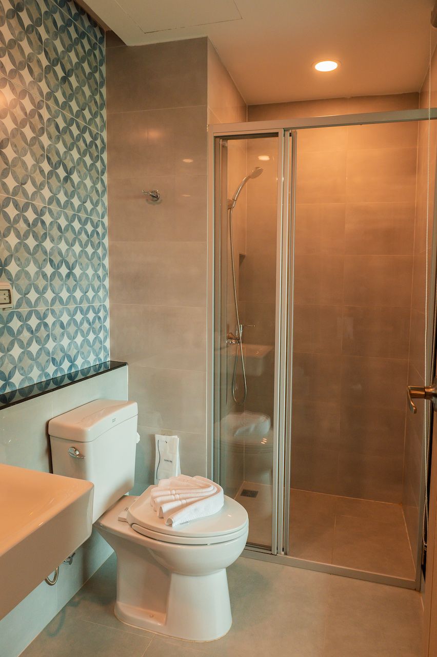 A modern bathroom with a toilet, a glass shower enclosure, and a patterned wall.
