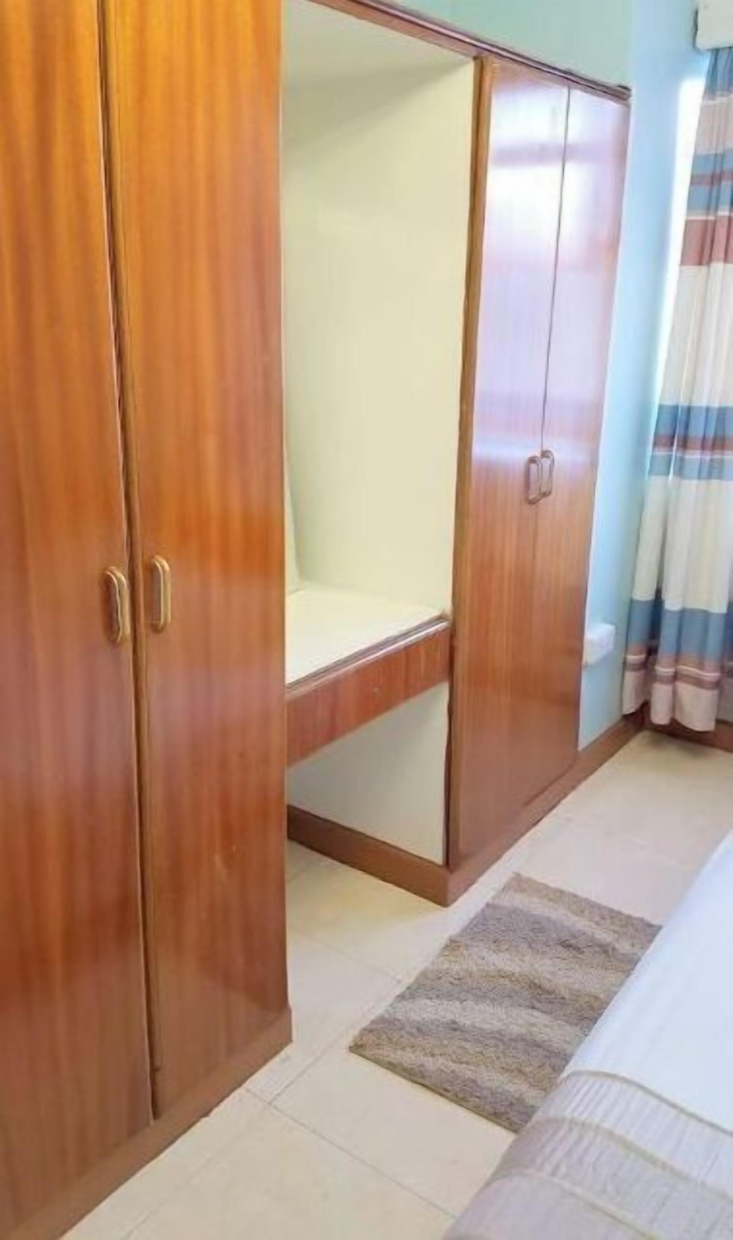 Una habitació amb un armari, un llit i una finestra amb cortines.