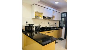 A modern kitchen with a black countertop, yellow cabinetry, and white upper cabinets. - Tastefully furnished 2 bedroom apartment in  Kilimani (Nairobi)