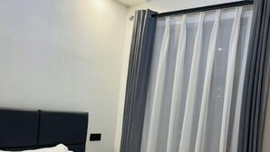 A hotel room with a bed, a headboard, a window with curtains, and a light fixture above the bed. - Tastefully furnished 2 bedroom apartment in  Kilimani (Nairobi)