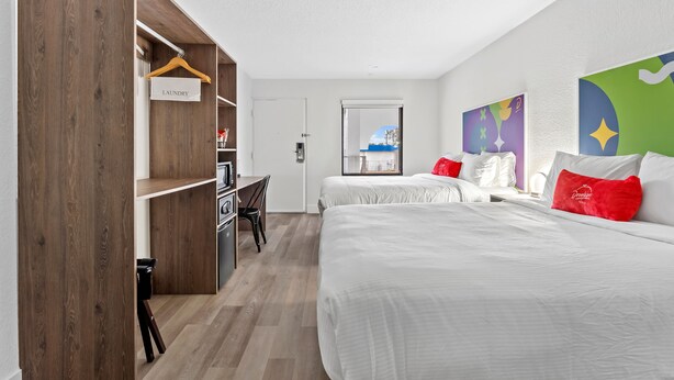 Habitación de hotel con dos camas, un armario de madera, un escritorio y vistas a la ciudad.