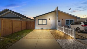 Une maison de plain-pied avec une porte d’entrée, un garage et une allée menant à une voiture garée.