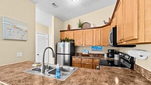 A kitchen with granite countertops, stainless steel appliances, wooden cabinets, and a microwave. - 5 Min Walk to Sand | King Bed | Private Yard! (Panama City Beach)