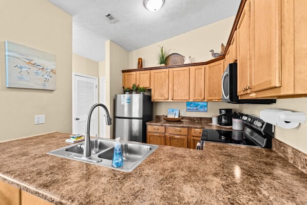 A kitchen with granite countertops, stainless steel appliances, wooden cabinets, and a microwave.