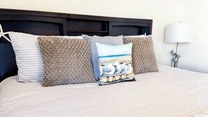 A bed with striped bedding, three pillows with different patterns, and a lamp on the side. - 5 Min Walk to Sand | King Bed | Private Yard! (Panama City Beach)