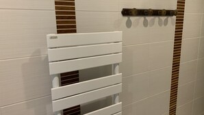 Un sèche-serviettes blanc, doté de barres horizontales, fixé au mur qui présente un motif à rayures.