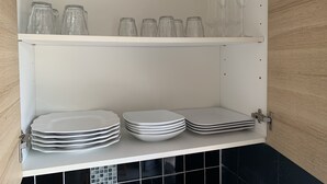 Un meuble de cuisine contenant de la verrerie et des assiettes empilées.