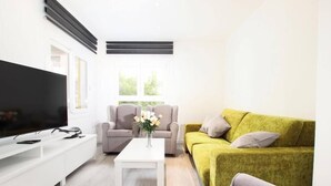 A modern living room with a flat-screen TV, a white coffee table, a grey sofa, and a yellow sofa. - Apartamento Rieres, Modern apartment next to the beach Port Pollensa (Port de Pollença)
