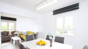 A modern living room with a white dining table, grey chairs, a sofa, and a coffee table. - Apartamento Rieres, Modern apartment next to the beach Port Pollensa (Port de Pollença)
