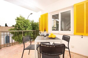 Un balcon avec une table dressée pour quatre personnes, agrémenté d’une bouteille de vin, de verres et d’une assiette de citrons.
