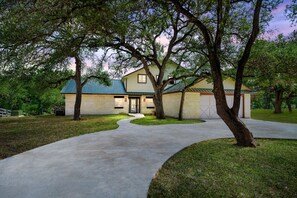A house with a curved driveway, a garage, and a well-maintained lawn.