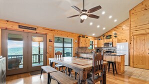 A wooden interior with a dining table, chairs, a ceiling fan, and a kitchen area. - Hillside views, private swimming pool, less than 5-minute drive to THE Frio River (Concan)
