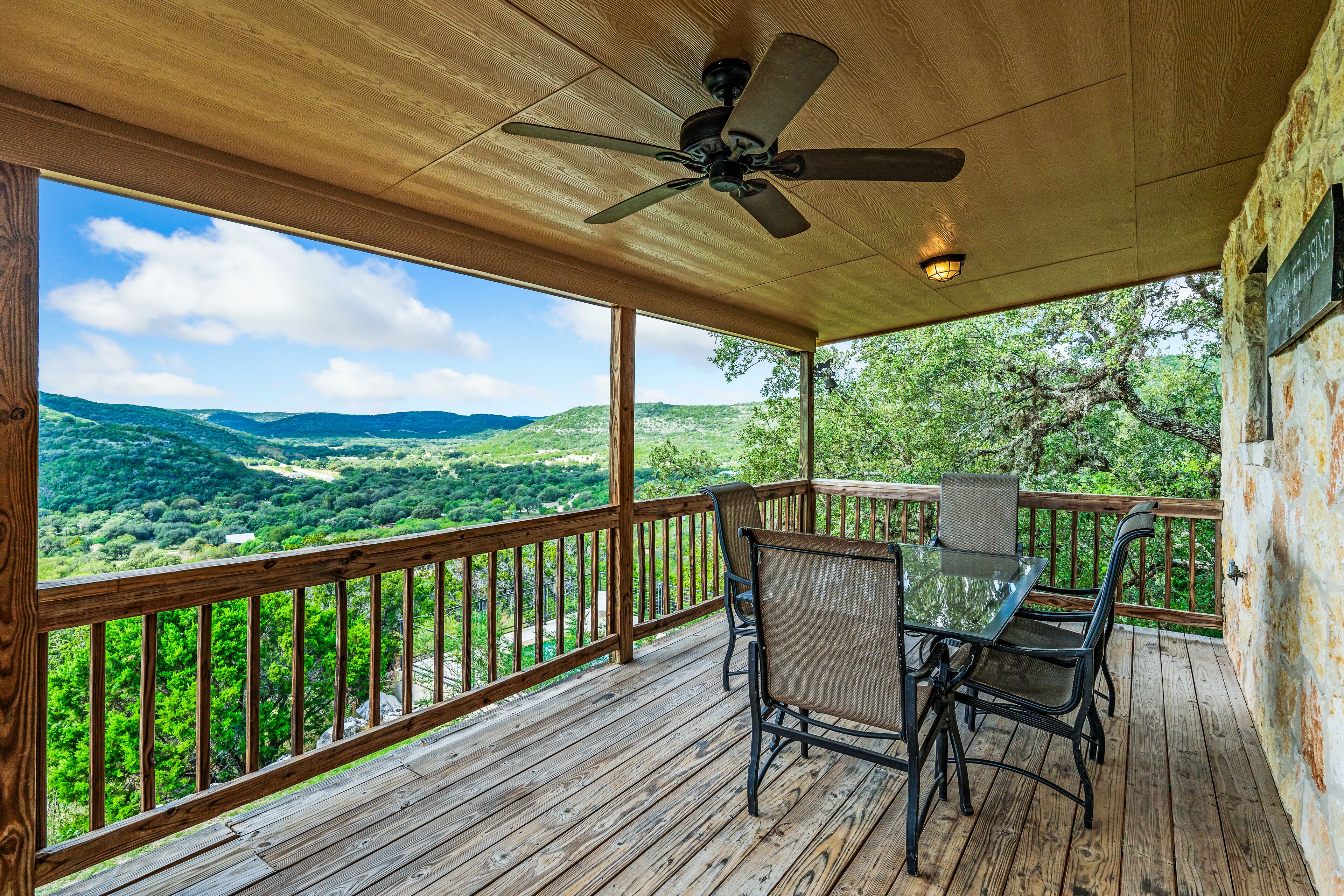 A wooden deck with a table and chairs, overlooking a scenic landscape.