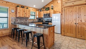 A kitchen with wooden cabinets, a central island with stools, a microwave, an oven, and a refrigerator. - Hillside views, private swimming pool, less than 5-minute drive to THE Frio River (Concan)