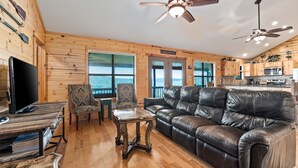 A cozy cabin interior with a leather sofa, wooden dining table, and ceiling fans. - Hillside views, private swimming pool, less than 5-minute drive to THE Frio River (Concan)